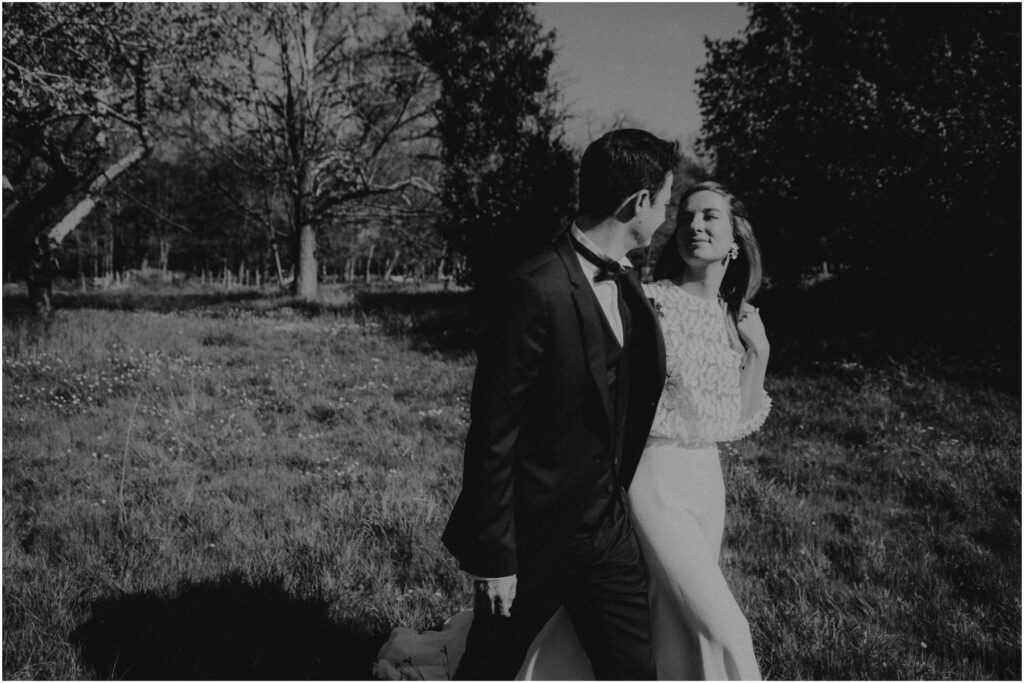 Couple de mariés marchant dans l'herbe et photographié par Grain de Clic Photographie.