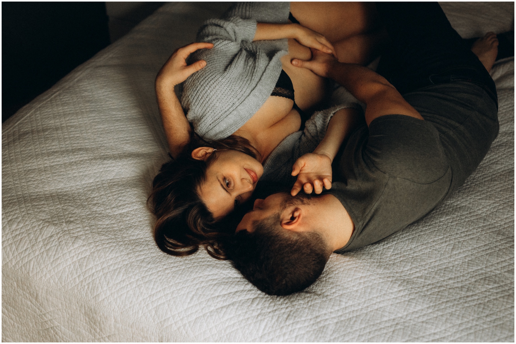 Couple allongé sur le lit lors d'une séance photo grossesse.