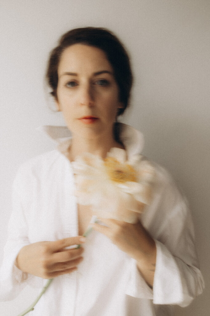 Portrait d'une femme assise tenant une fleur dans les mains avec du rouge à lèvres.