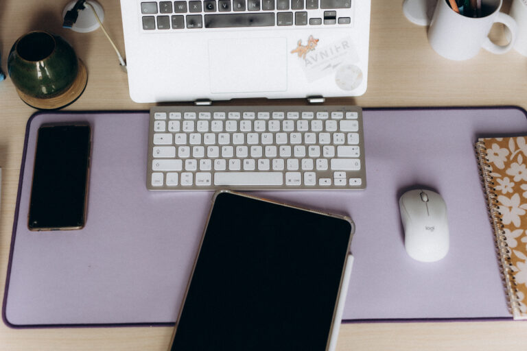 Ordinateur, clavier et souris posés sur un bureau en bois.