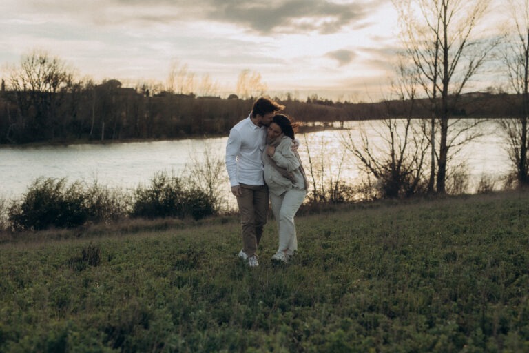 Un couple marchant dans une prairie au coucher du soleil.