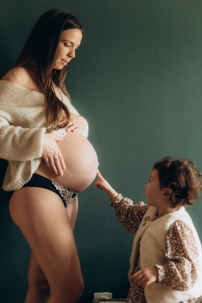 Une femme enceinte debout devant sa petite fille.