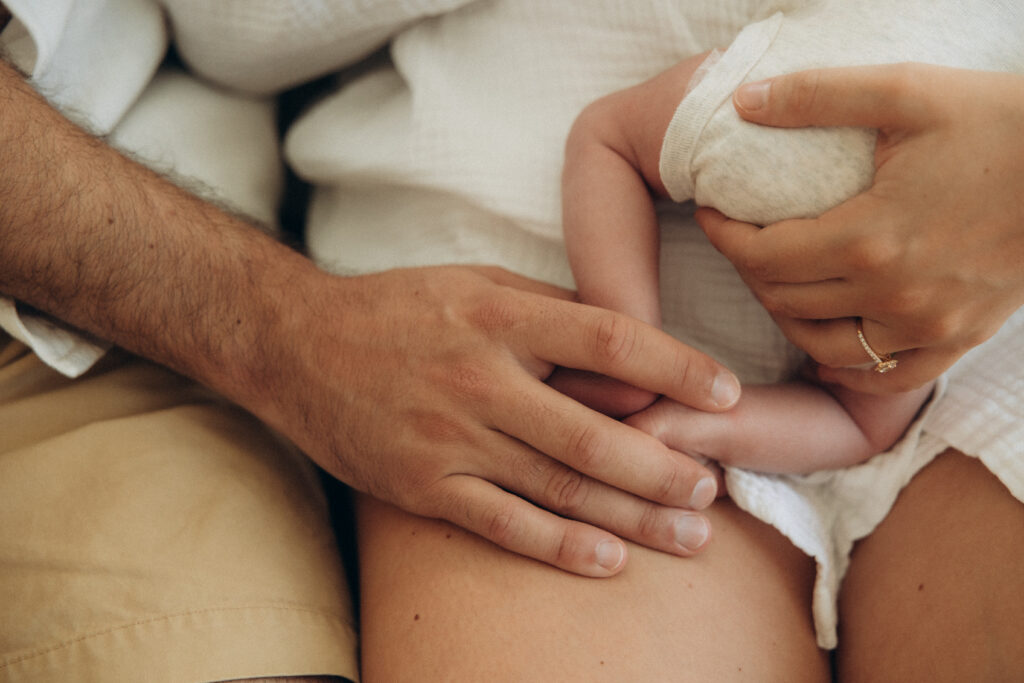 Petits pieds de bébé tenus dans les mains de son papa.