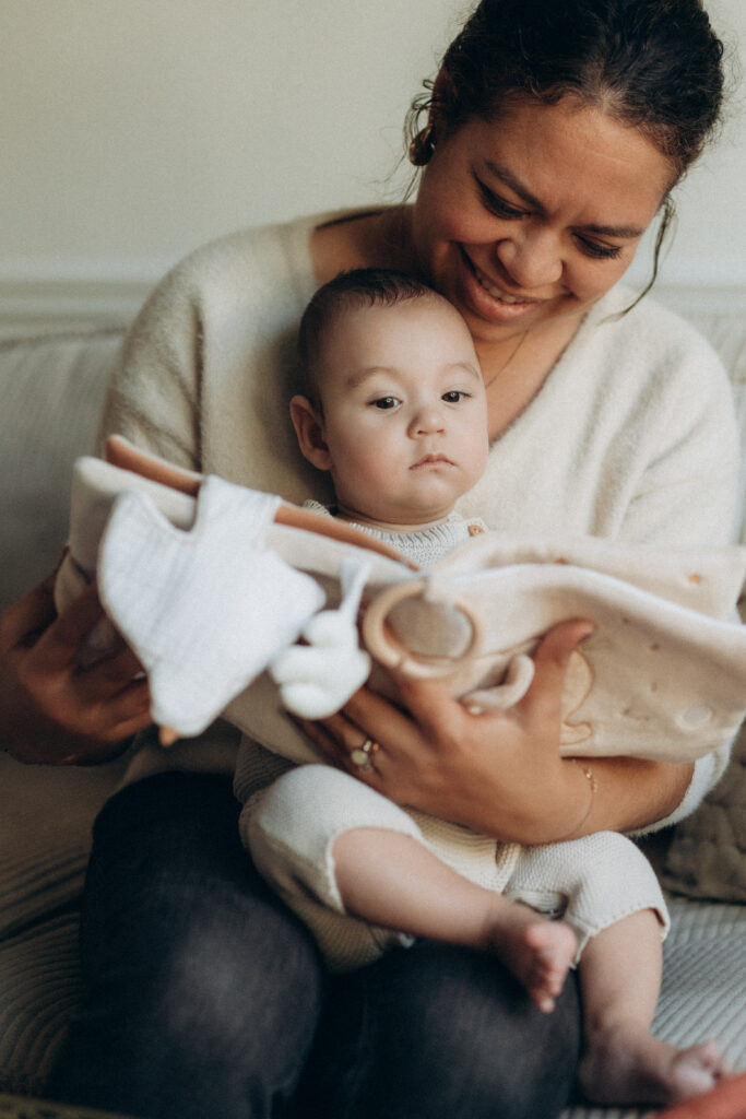 Une maman qui tient dans ses bras un bébé et qui lui lit un album enfant.