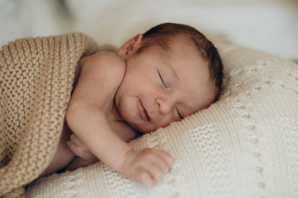 Bébé endormi sur un plaid beige.