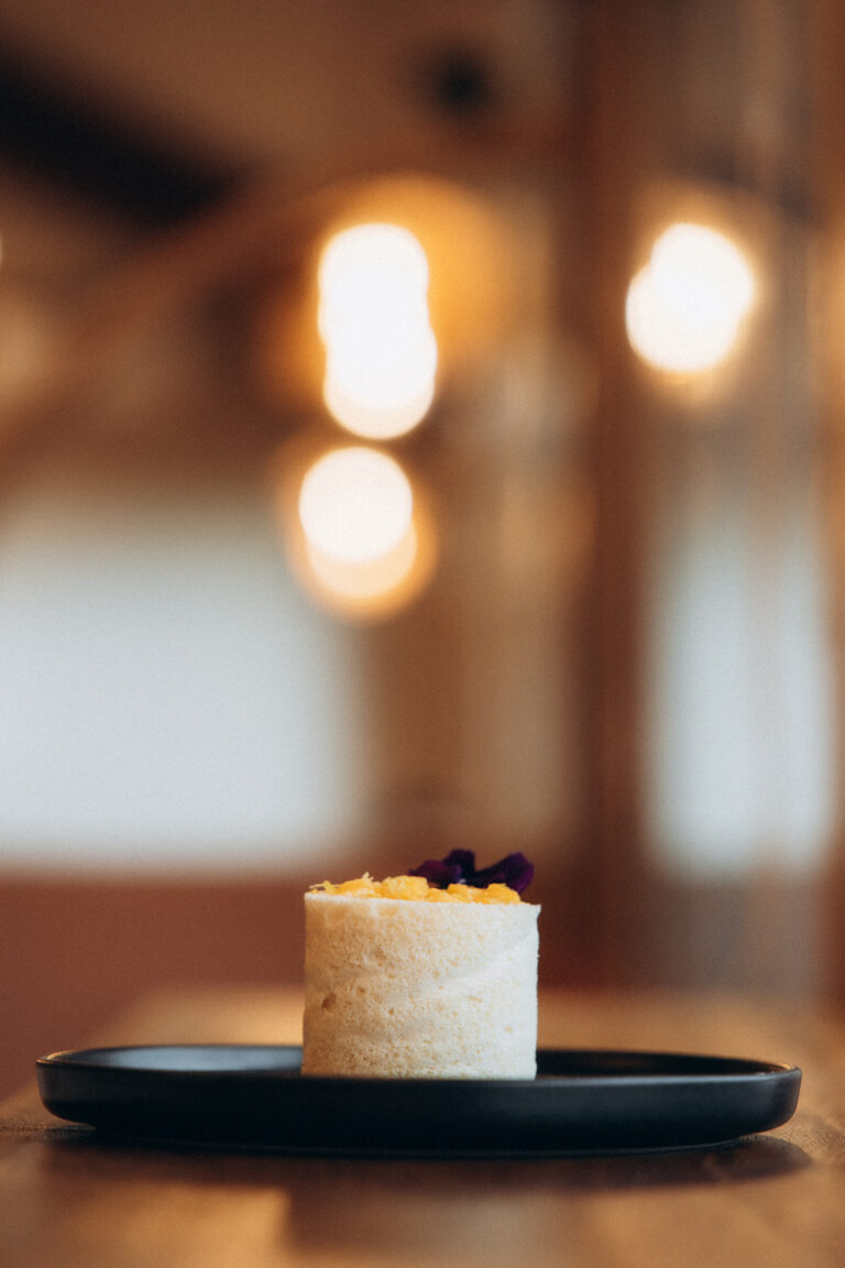 Un pâtisserie individuelle blanche disposée sur une assiette noire.