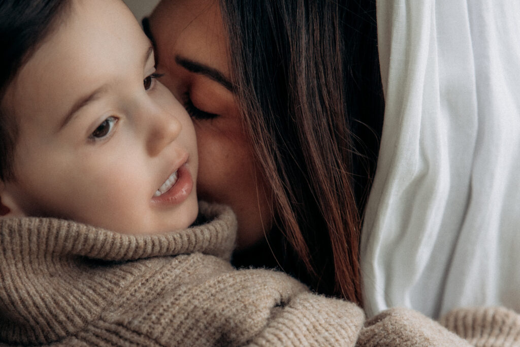 Une maman embrasse son petit garçon sur la joue.