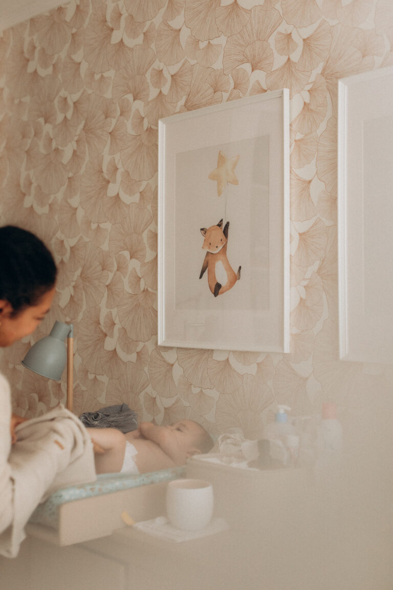 Un cadre blanc avec une illustration de renard dans une chambre de bébé.