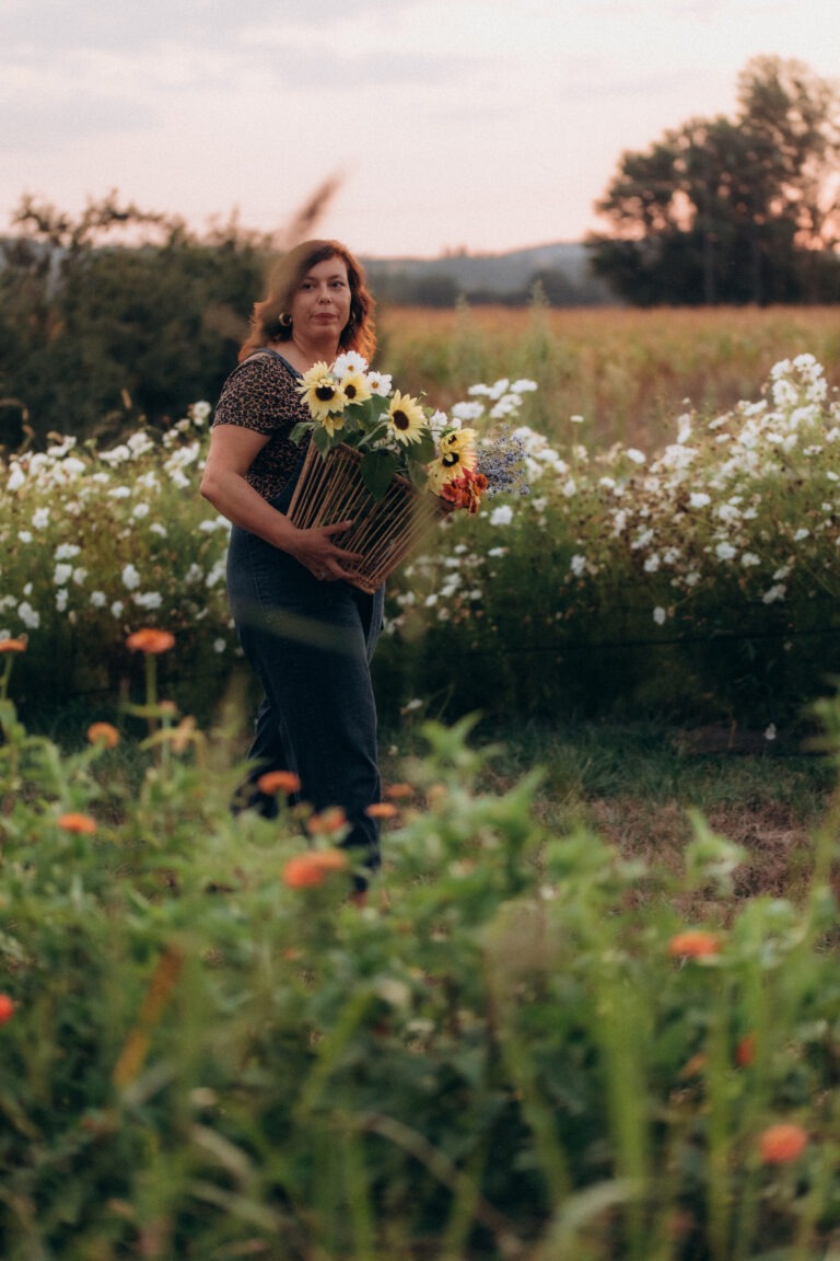 Une femme au milieu d'un champ de fleurs au coucher du soleil.