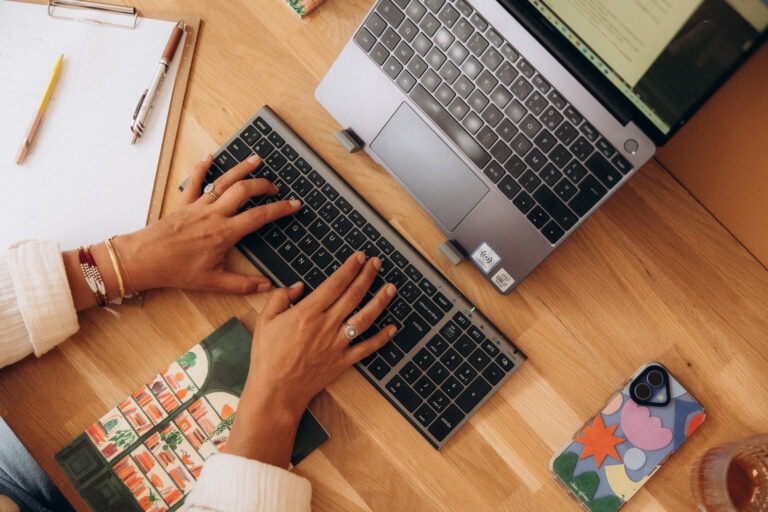 Deux mains de femme disposées sur un clavier d'ordinateur.