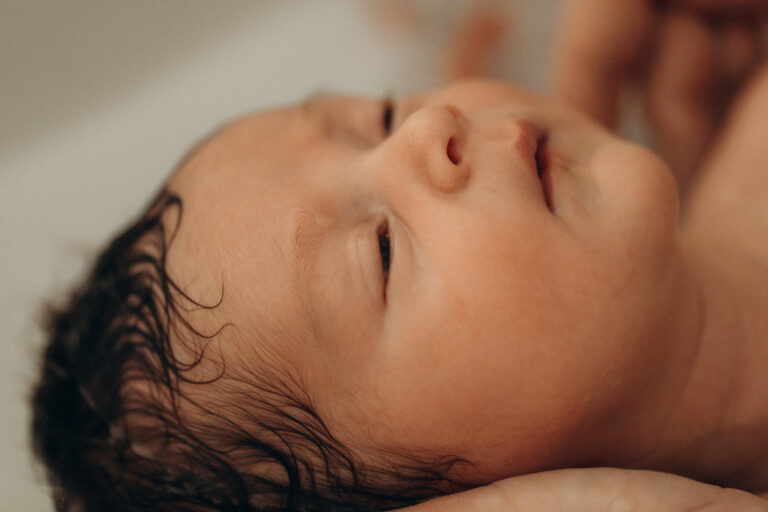 Un visage de bébé apaisé dans un bain.